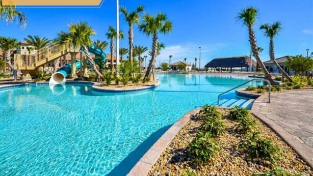 Ein Swimmingpool im Oasis Club Resort mit Wasserrutsche und Palmen.