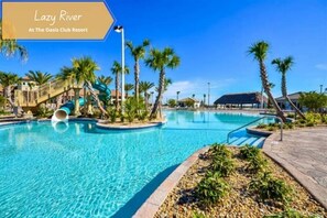 A swimming pool at The Oasis Club Resort with a water slide and palm trees. - 9 BR Villa Steps to Oasis Resort & Waterpark/Pets OK/Game Room. (Davenport)