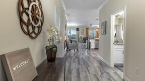 Ein modernes Interieur mit Holzboden, einem Willkommensschild, einer Wanddekoration und einem Blumentopf.