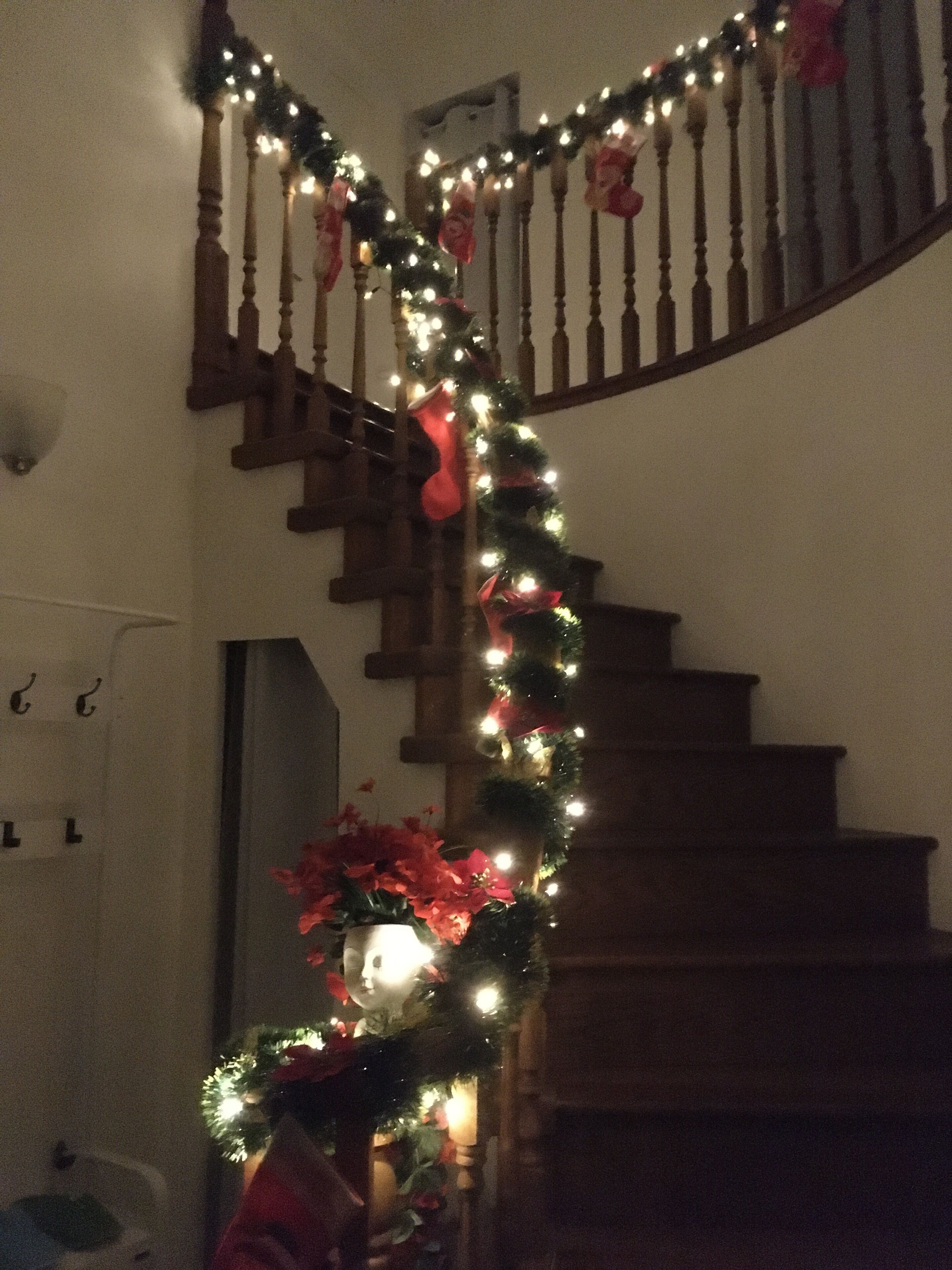 A staircase with a garland of lights and red stockings.