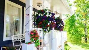 Une véranda avec des balustrades blanches, un banc blanc et des jardinières suspendues.