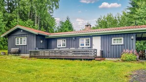 A two-story cabin with a porch, surrounded by greenery. - Nice home in Sagstua with lake view (Sagstua)