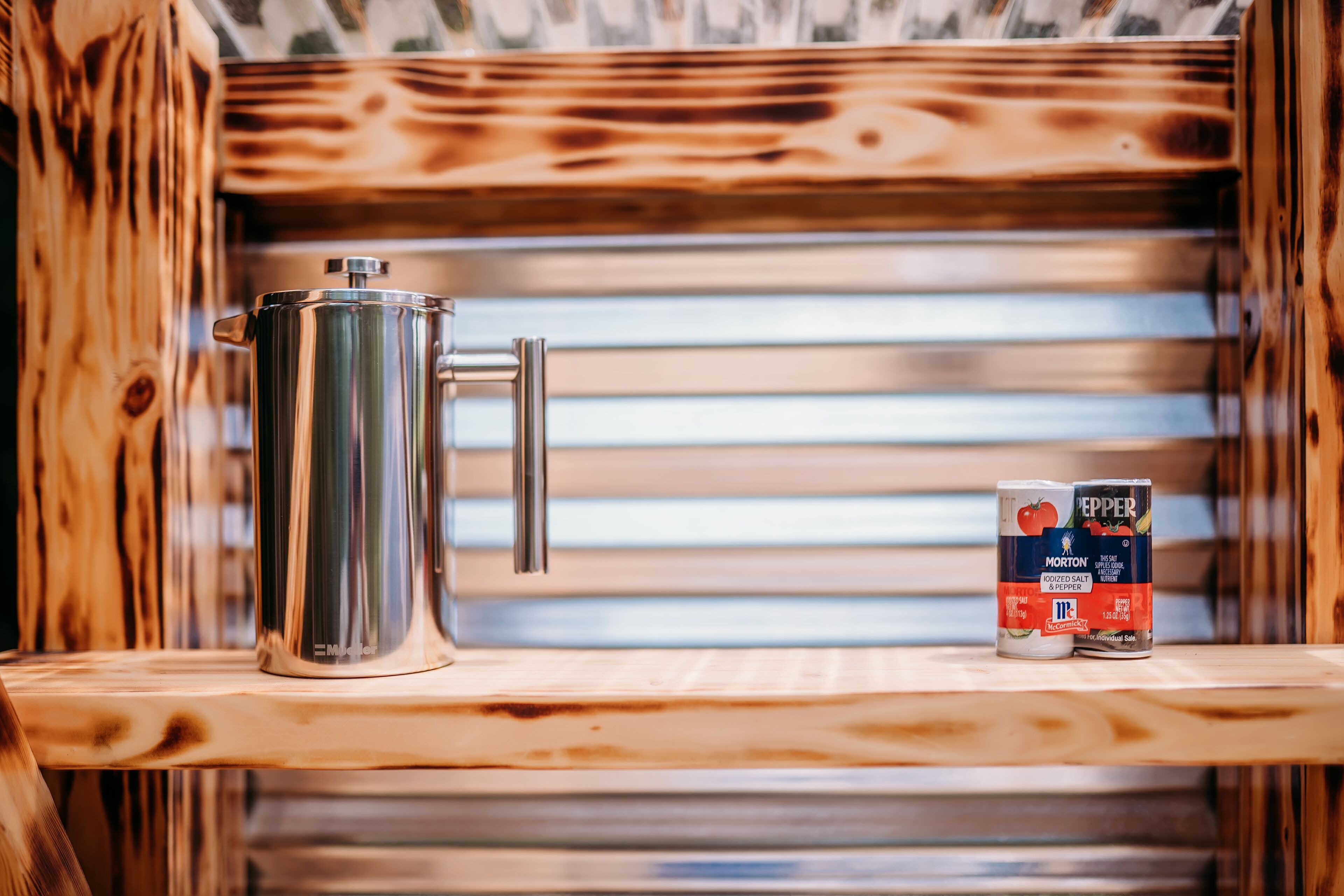A stainless steel pot on a wooden shelf with a can of Morton Kosher Salt & Pepper beside it.