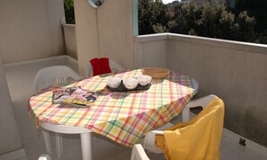 A small outdoor table with a plaid tablecloth, a magazine, and a basket. - Flat With Balcony and Shared Pool (Lignano Sabbiadoro)