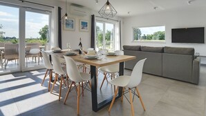 Una sala de estar moderna con comedor, ventanas amplias y un televisor de pantalla plana.
