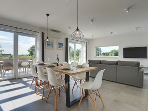 A modern living space with a dining area, a sofa, and a TV. - Villa Mauri - Medulin - Large Garden, Very Quiet Location (Medulin)