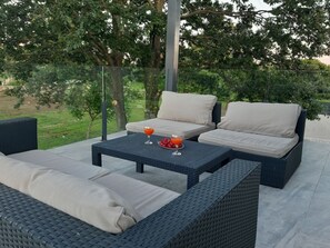 An outdoor seating area with wicker furniture and a glass table, surrounded by greenery. - Villa Mauri - Medulin - Large Garden, Very Quiet Location (Medulin)