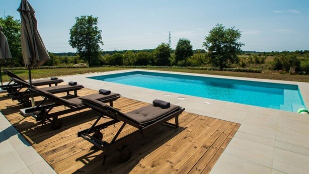 Una piscina con sillas de descanso y una terraza de madera.