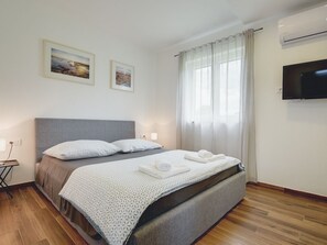 A hotel room with a bed, a flat-screen TV, two framed pictures on the wall, and a window with curtains. - Villa Mauri - Medulin - Large Garden, Very Quiet Location (Medulin)