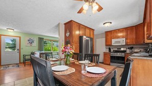 Un comedor con una mesa de madera, sillas y un jarrón de flores.