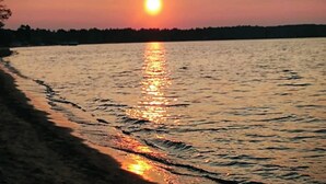 Un atardecer sobre un cuerpo de agua tranquilo, con la orilla visible.