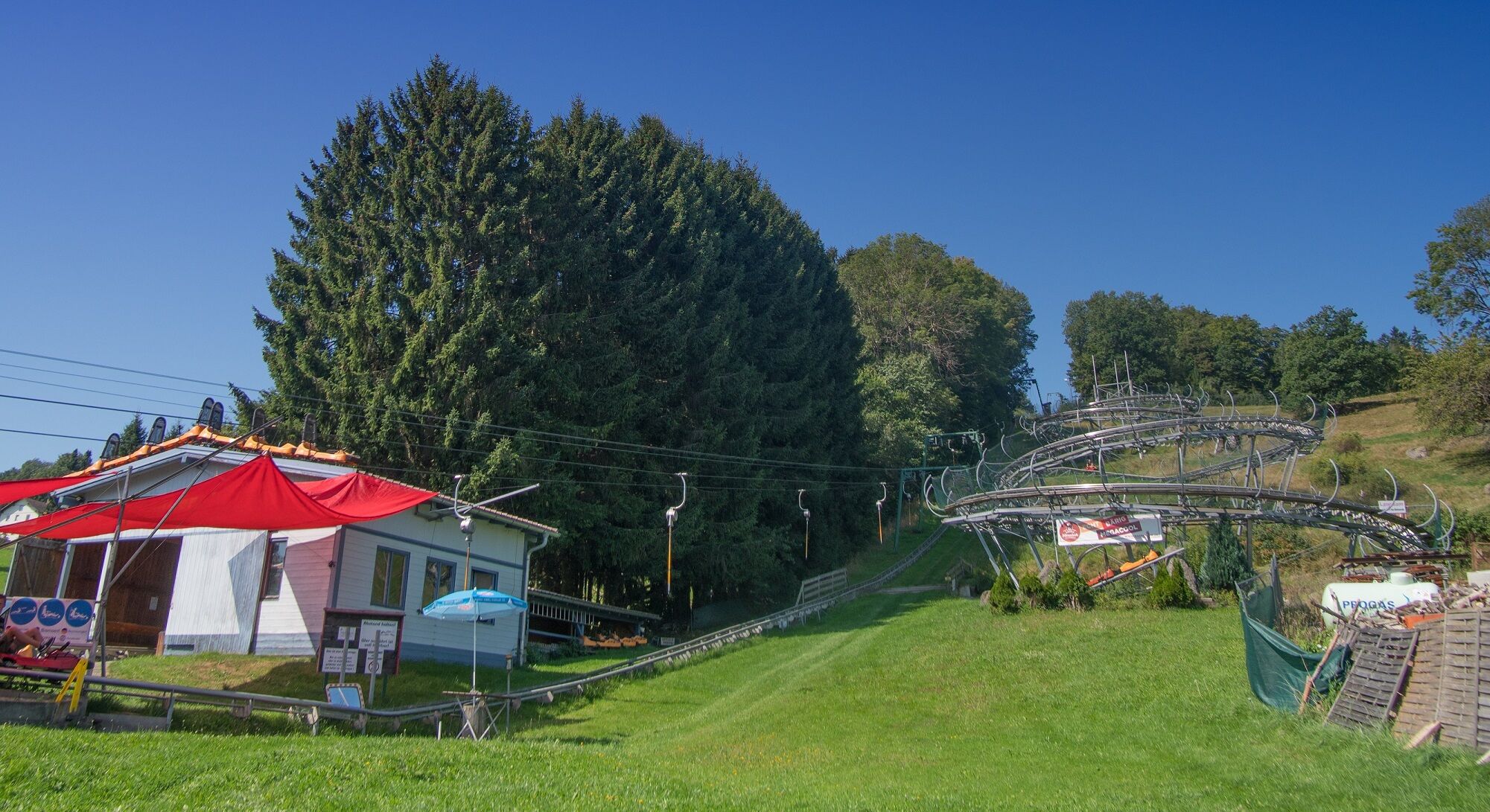 Een skilift met stoeltjeslift en een gebouw met een rood dak en een blauwe parasol.