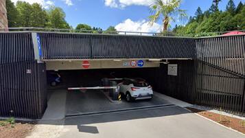 A gated parking area with a white car inside, a no-entry sign, and a directional sign indicating a 2-lane road.