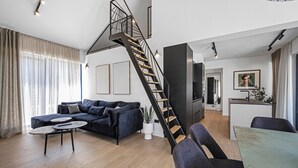Ett modernt vardagsrum med en trappa, en soffa, ett soffbord och en matplats.