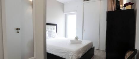 A hotel room with a bed, a wardrobe, a chair, and a window.