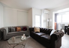A modern living room with a grey sofa, a dark brown sofa, and a glass coffee table.