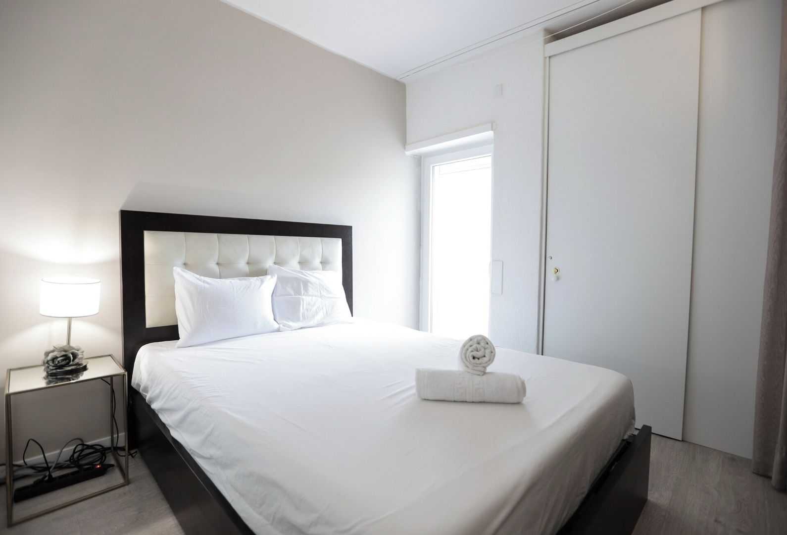 Ein Hotelzimmer mit einem Bett, einem Nachttisch mit Lampe und einer Tür.