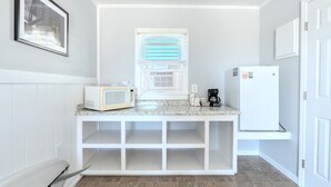 A compact kitchen with a microwave, coffee maker, and a refrigerator.