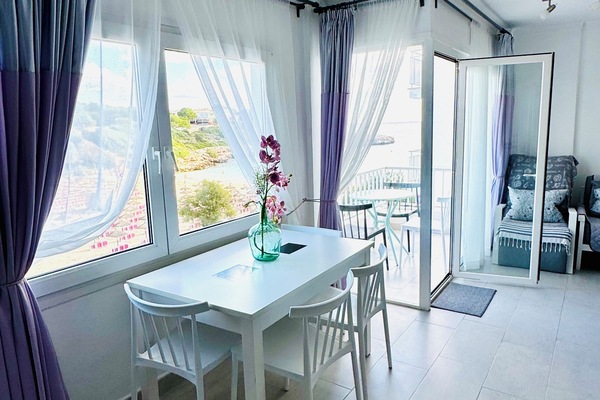 Bright, sun-filled living space with large windows framing the Mediterranean Sea