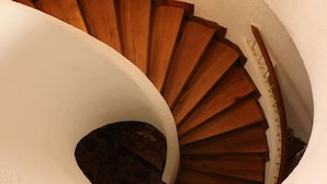 A spiral staircase with wooden steps and a white wall.