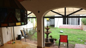 A patio area with a hammock, a fountain, and a chair.
