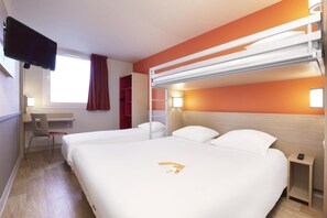 Ein Hotelzimmer mit zwei Betten, einem Schreibtisch, einem Stuhl, einem Fernseher und einem Fenster mit Vorhängen.