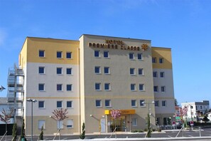 A hotel building with a sign reading 'HOTEL PREMIERE CLASSE' and a reception area with a flower display.