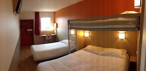 A room with two bunk beds, a desk, a chair, and a wardrobe.