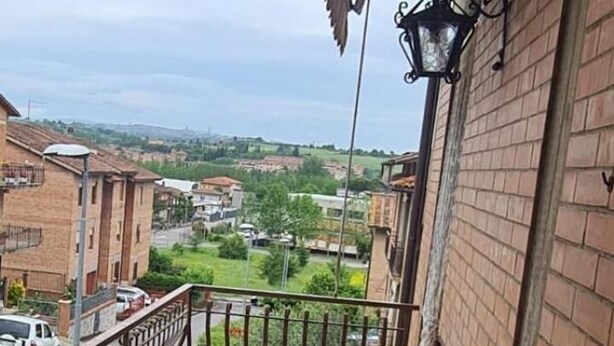 Ein Balkon mit Tisch und Stühlen, Blick auf die Stadt und eine Ziegelwand.