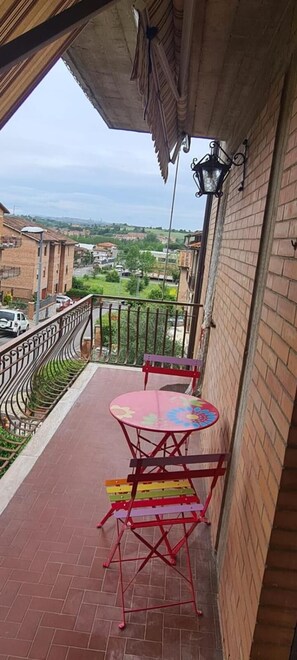 A balcony with a table and chairs, a view of the city, and a brick wall. - Siena-crete Senesi-val Dorcia (Asciano)