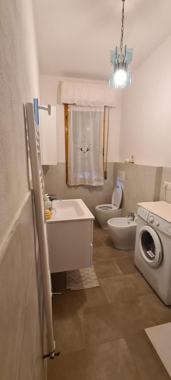 Egy kis fürdőszoba mosdókagylóval, WC-vel és mosógéppel.
