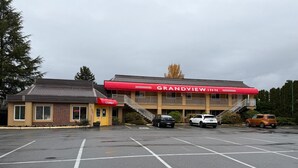 A Grandview Inn with a red awning, a lobby, and a parking lot with several cars. - Grandview Inn (Surrey)