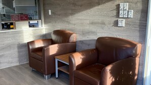A corner seating area with two brown leather chairs and a small wooden table. - Grandview Inn (Surrey)