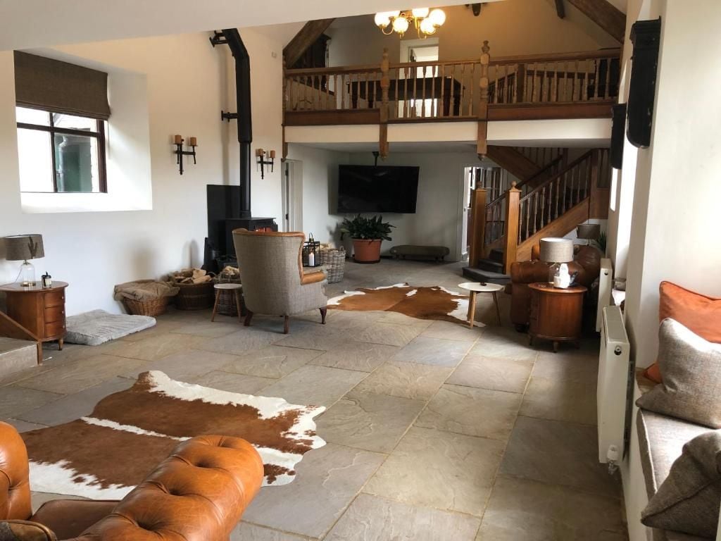 Amplia sala de estar con chimenea, televisor montado en la pared y escalera que conduce a un nivel superior.