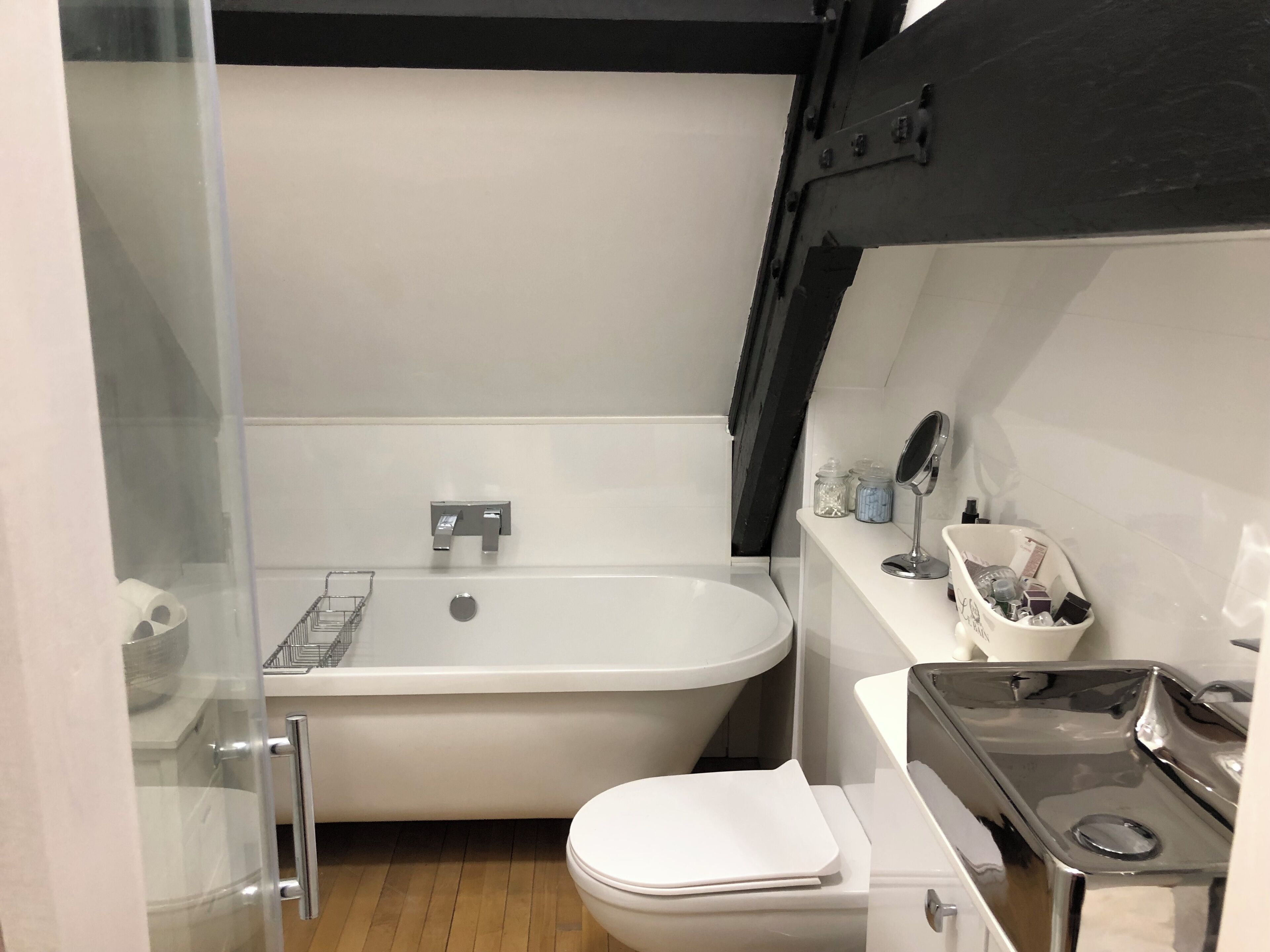 Ein kleines Badezimmer mit einer weißen Badewanne, einer Toilette und einem kleinen Waschbecken.