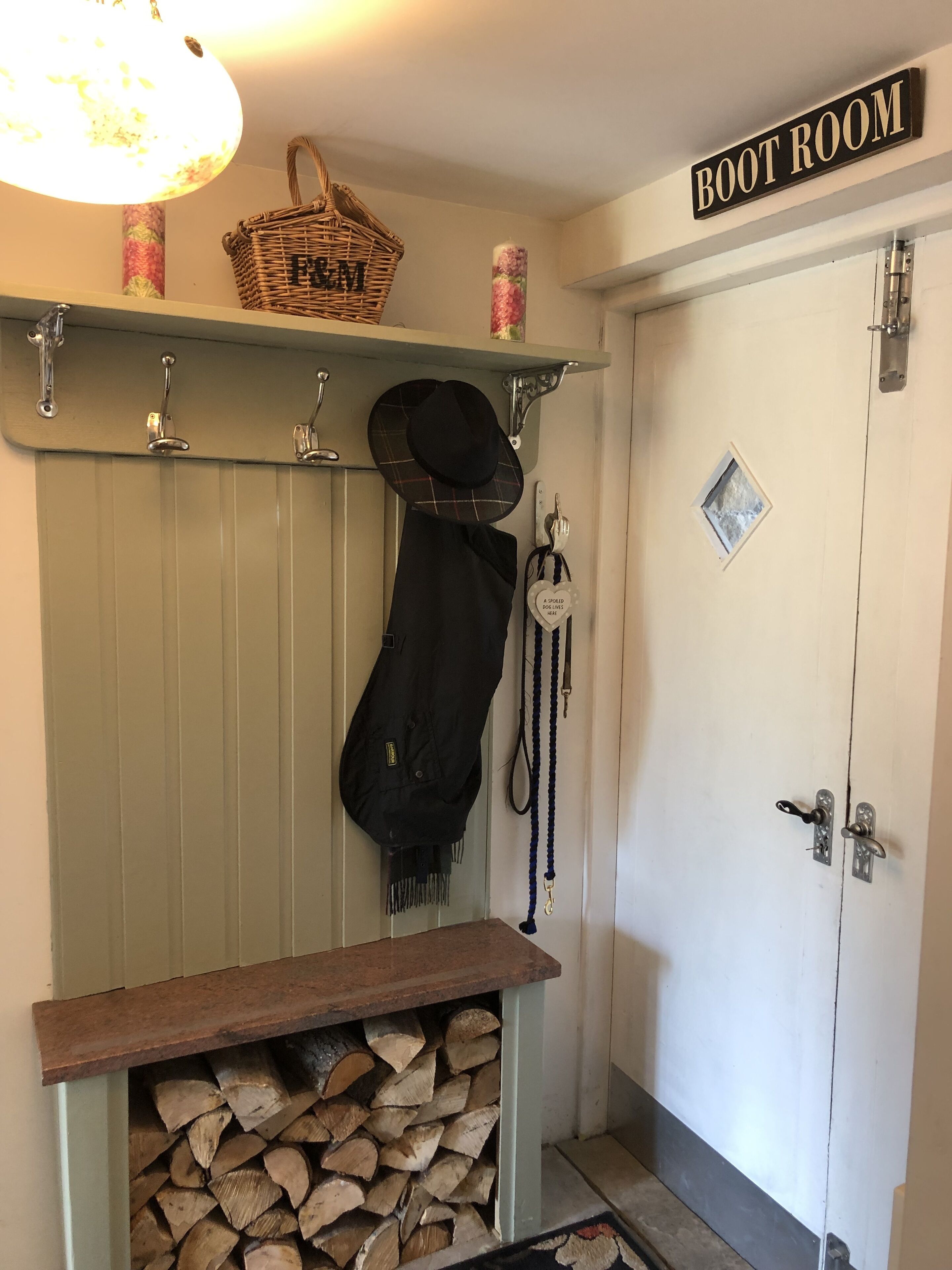 A boot room with a wooden bench, a basket, a hat, and a coat hanging on hooks.