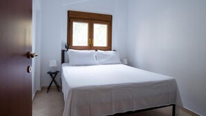 Een hotelkamer met een bed, nachtkastje, lamp en raam.