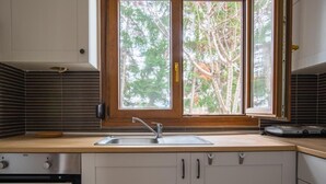 Een keuken met een raam, roestvrijstalen apparatuur en een houten aanrecht.