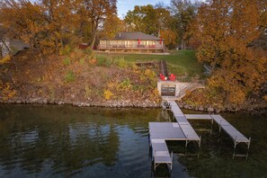 A lakeside property with a dock, a house with a balcony, and autumn foliage. - Lake Front|Clear Water|PaddleBoard|Dock|Sleep12 (Alexandria)