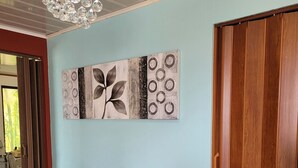 A hallway with a wooden door, a wall-mounted artwork, and a decorative vase.