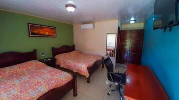Une chambre avec deux lits, un bureau, une chaise et un ventilateur de plafond.