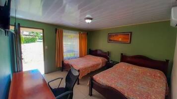 A hotel room with two single beds, a desk, a chair, and a window with curtains.