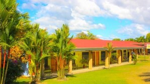 A hotel with a red roof, palm trees, and a clear sky.
