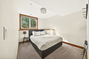 A bedroom with a bed, a window, a lamp, and a radiator. - Fernie Alpine Chalet (Fernie)