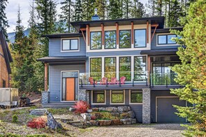A modern two-story house with a stone foundation, large windows, and a balcony with chairs. - Fernie Alpine Chalet (Fernie)