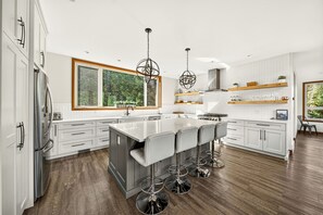A modern kitchen with a large island, bar stools, and pendant lighting.