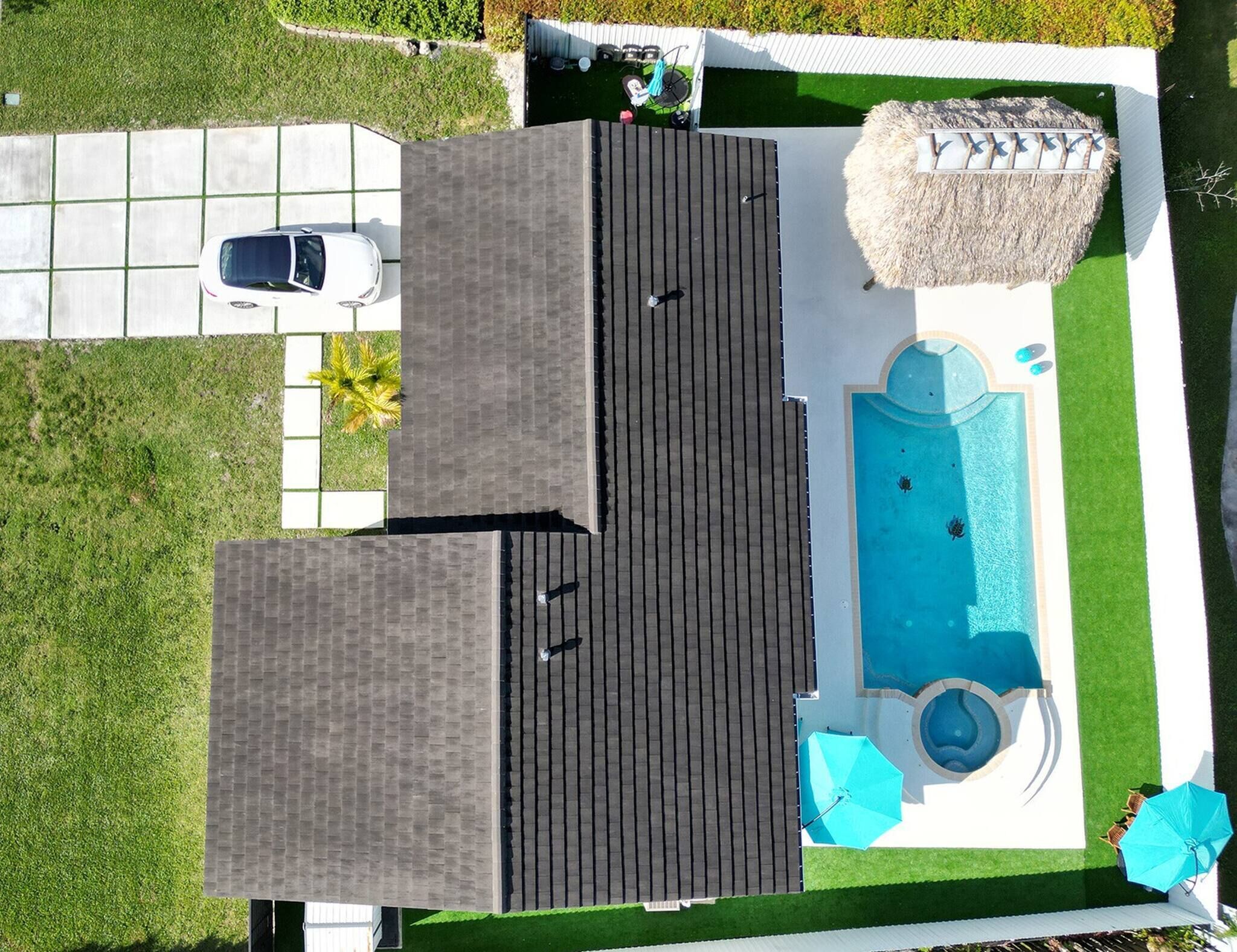 A rooftop with a swimming pool, a covered patio area, and a car parked nearby.