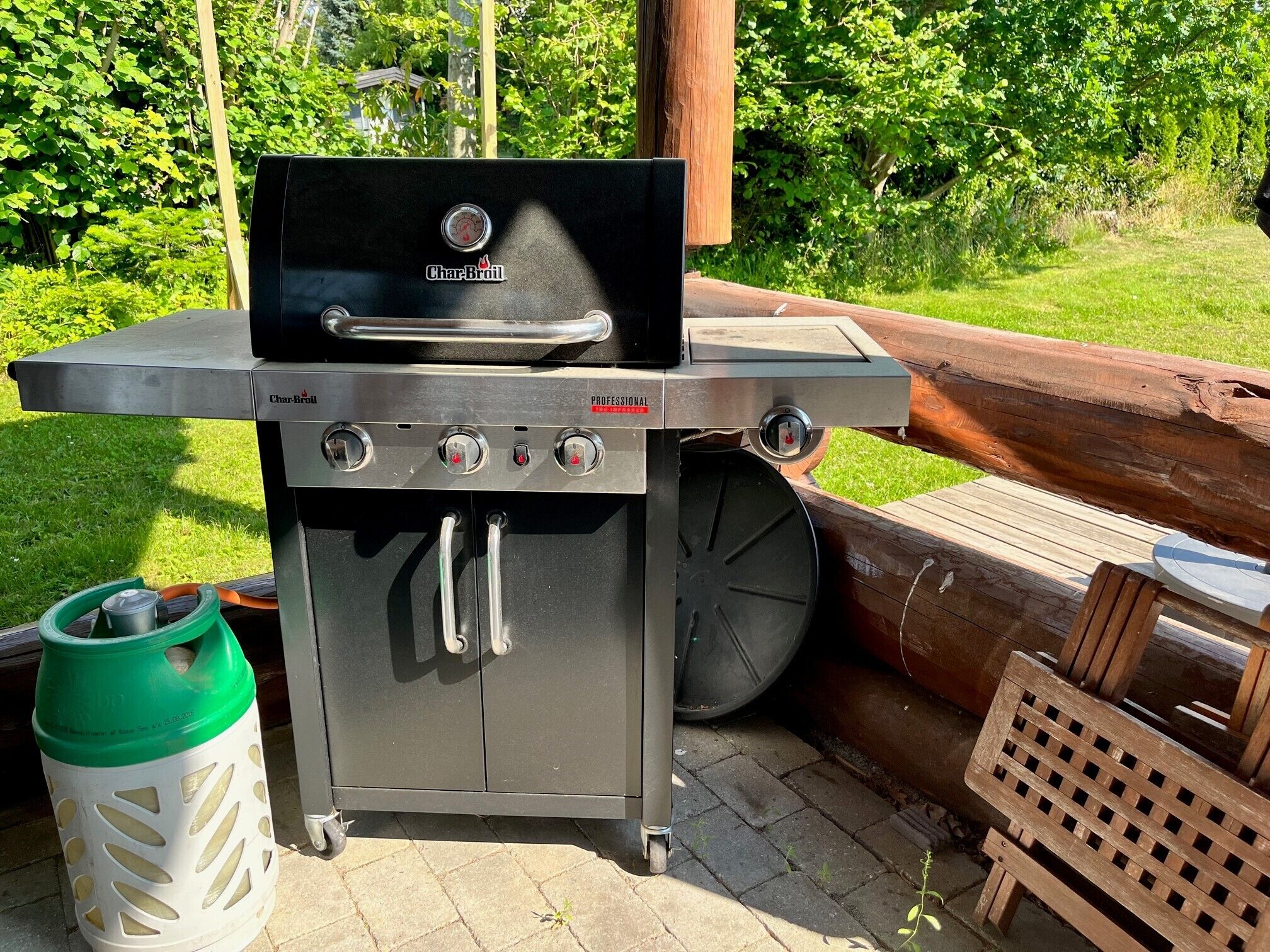 A Char-Broil portable grill with four control knobs, a gas tank, and a wheel for mobility.