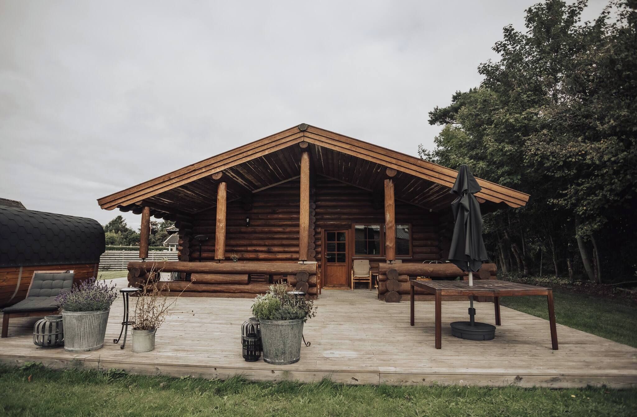 A log cabin with a porch, outdoor seating, and a grill area.