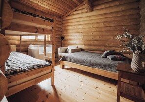 A cozy log cabin bedroom with bunk beds, a single bed, a chair, and a bedside table. - Fjordhygge, Cozy Log Retreat Near Sea & Forest - Sauna & Outdoor Living (Jægerspris)